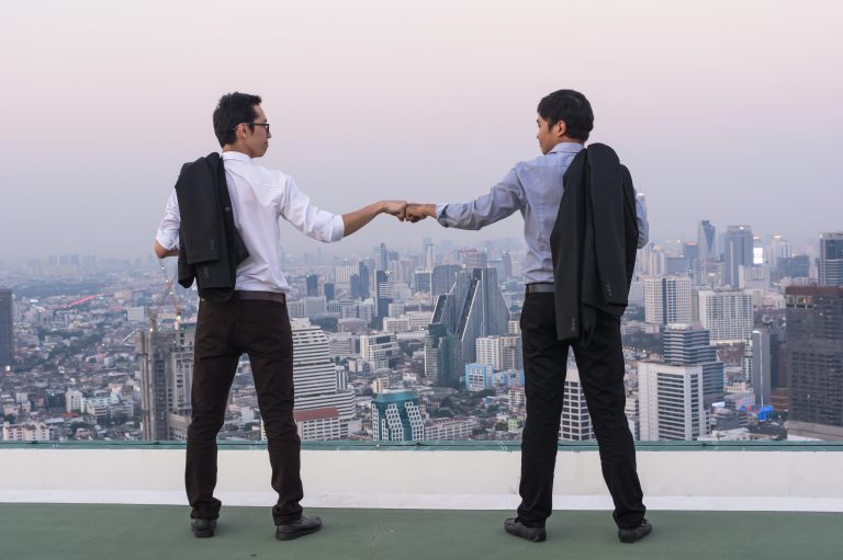 employee advocacy dwóch biznesmenów przybija piątkę na dachu